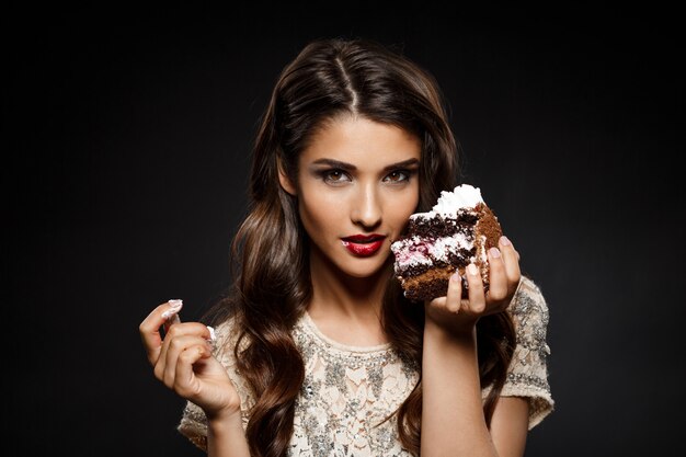 Sexy woman in creamy dress holding piece of cake