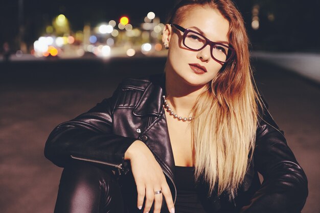 Sexy woman with long hair in leather clothes on night city street