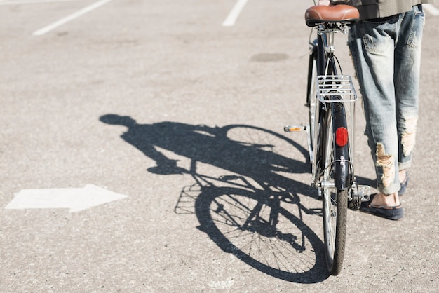 Free Photo shadow of man walking with bicycle on asphalt