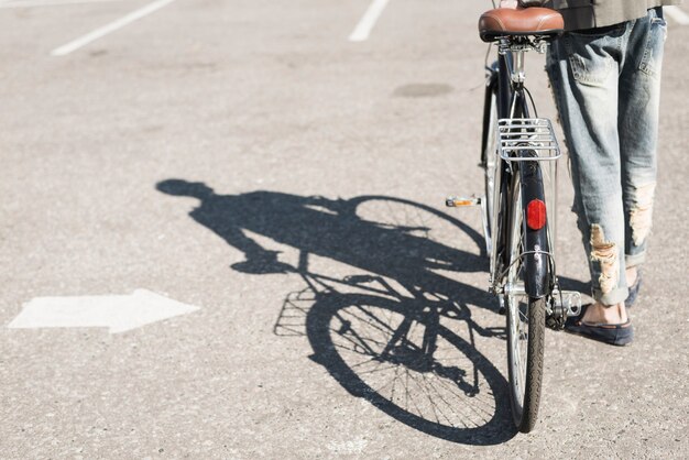 Shadow of man walking with bicycle on asphalt