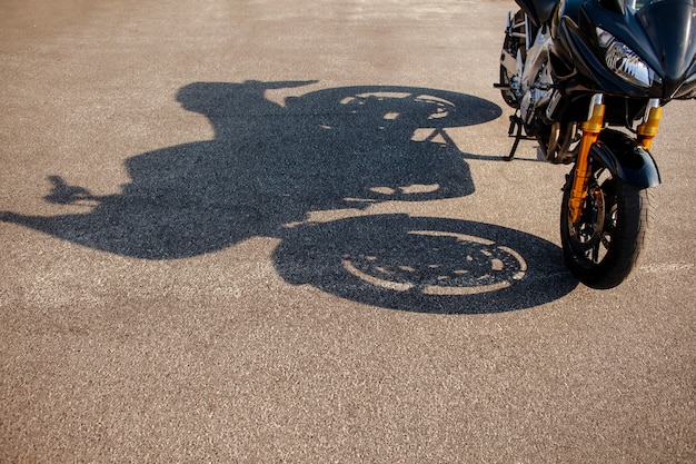 Free photo shadow of orange motorbike on asphalt