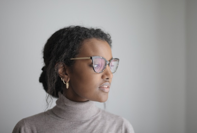 Free photo shallow focus of an african-american female with glasses wearing a gray turtleneck