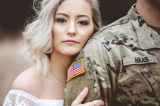 Free photo shallow focus of an attractive female holding an american soldier's arm