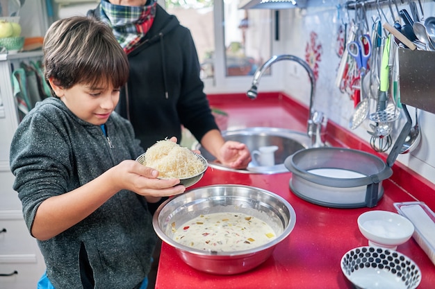 Shallow focus of a cheerful mother cooking with her little son in a kitchen