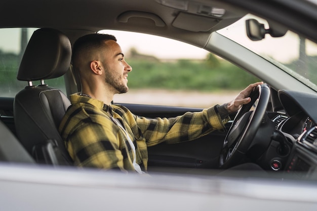 Shallow focus shot of a handsome Spanish Caucasian man sitting behind the wheel of a modern car