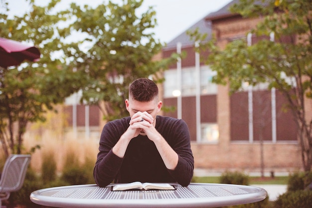 Shallow focus shot of a male praying with an open bible