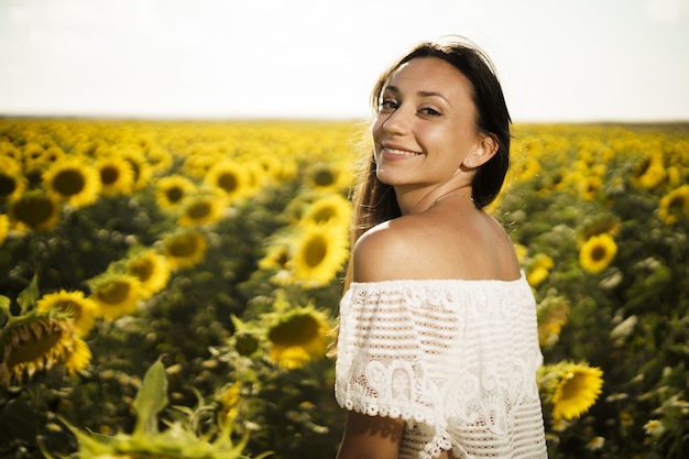 Shallow focus shot of pretty Caucasian female in a sunflower field at sunrise