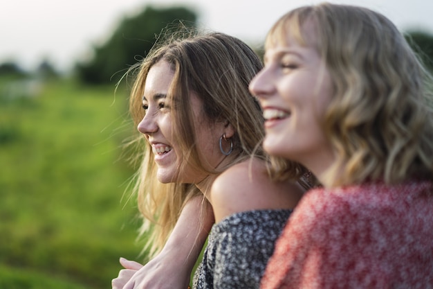 Shallow focus of two young cheerful women hugging in a park in Spain