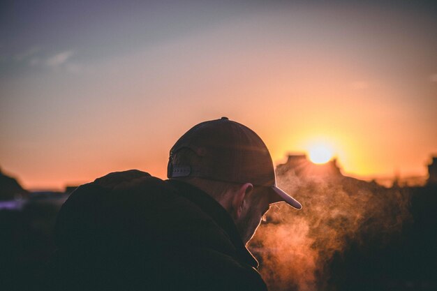 Shallow focused shot of a cap-wearing man's back during sunset golden hour.