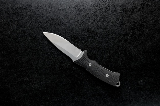 A sharp small kitchen knife with black handle on black table