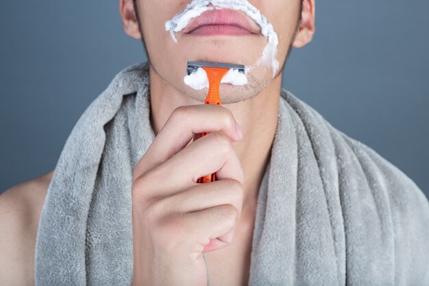 Shaving handsome guy shaved on the face on gray