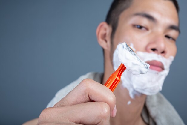 Shaving handsome guy shaved on the face on gray