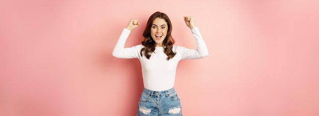 Free Photo she is a winner enthusiastic brunette girl celebrating jumping from happiness and shouting joyful ac