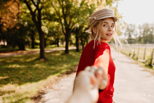 Shining blonde girl looking charmingly  following a person on the park path.