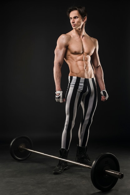 Shirtless athletic man posing with weight set