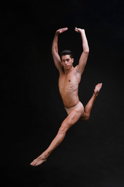 Shirtless dancer jumping with raised arms