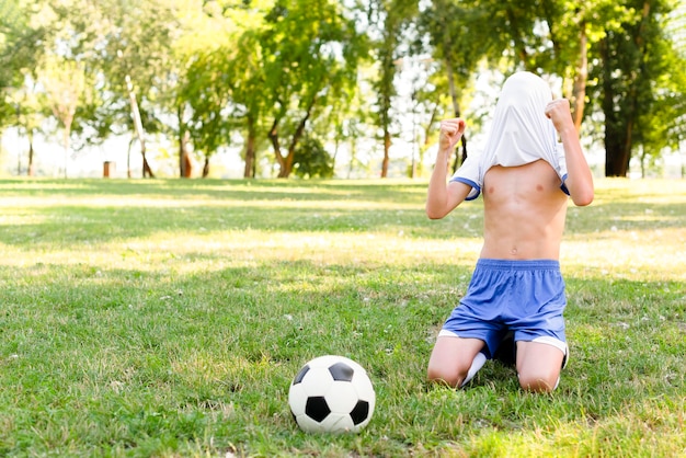 Shirtless kid being victorious after scoring a goal