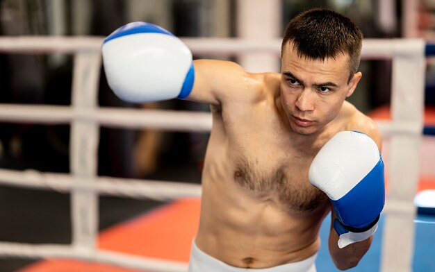 Shirtless male boxer practicing in the ring