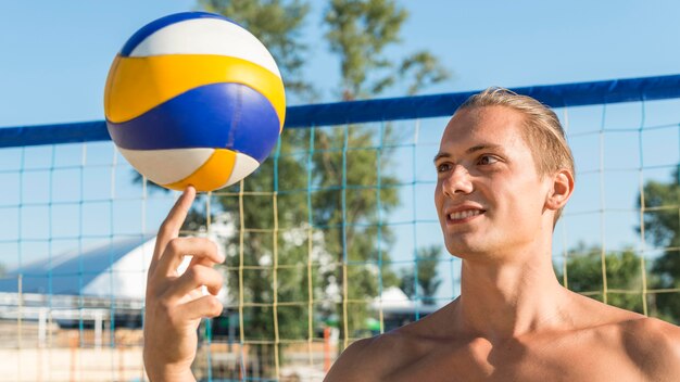 Shirtless male volleyball player holding ball with finger