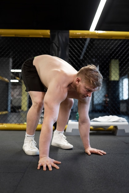 Shirtless man training at gym full shot