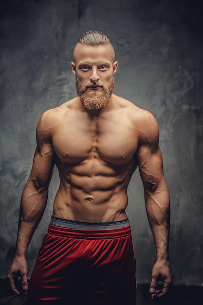 Free photo shirtless muscular man with beard posing over grey background.