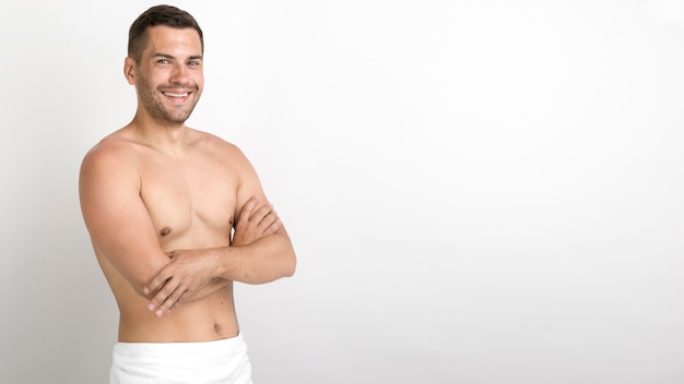 Shirtless young man standing with arm crossed