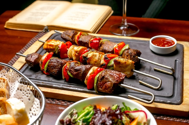 Shish kebab with colorful bell peppers served with ketchup and fresh vegetables