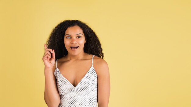 Shocked. African-american beautiful woman's portrait isolated on yellow  wall with copyspace. Stylish female model. Concept of human emotions, facial expression, sales, ad, fashion, youth.