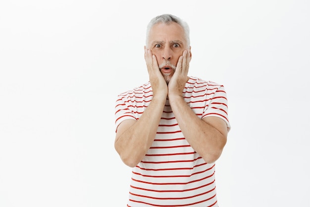 Shocked and amazed old bearded man react to stunning news, look wondered