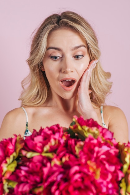 Free photo shocked blonde young woman looking at flower bouquet