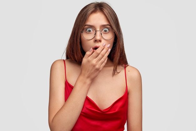 Shocked brunette young woman posing against the white wall