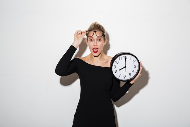 Shocked business woman holding clock.