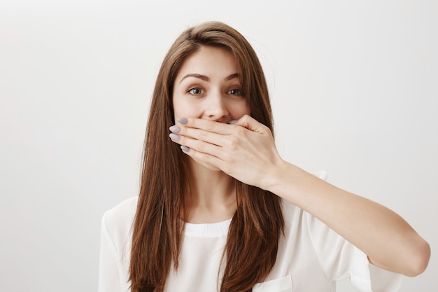 Free photo shocked cheerful girl cover mouth with palm, stop herself from talking