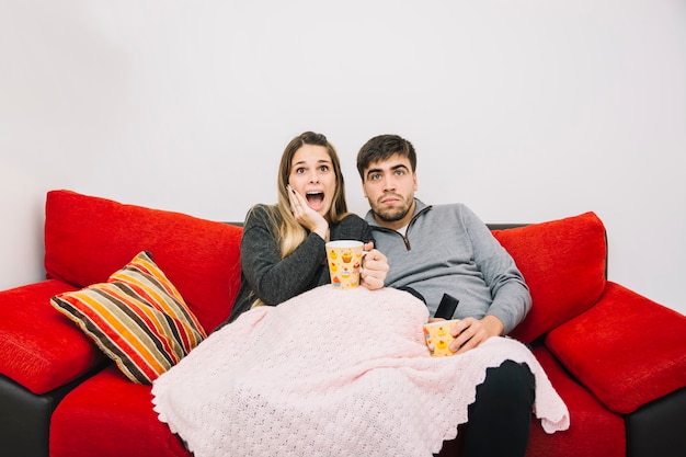 Shocked couple sitting on sofa watching movie