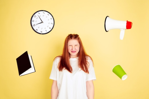 Shocked, deadline. Caucasian young woman's portrait on yellow studio background, too much tasks. How to manage time right. Concept of working, business, finance, freelance, self management, planning.