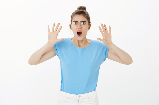 Shocked and frustrated woman in glasses gasping, looking at something horrible