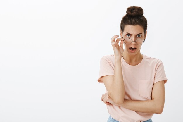 Shocked gasping young stylish woman posing against the white wall