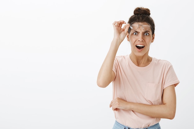 Shocked gasping young stylish woman posing against the white wall