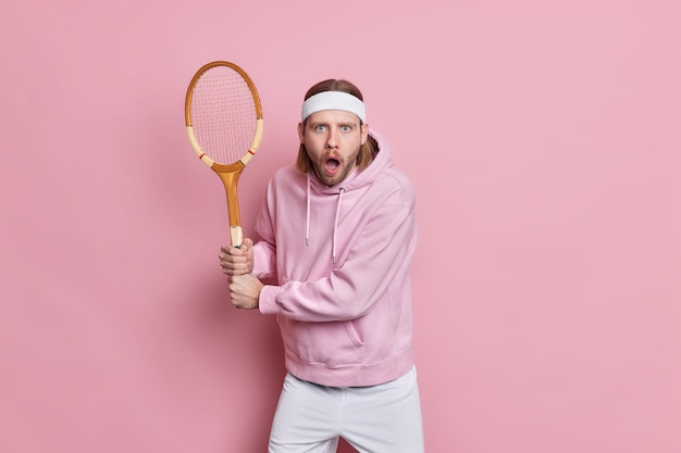 Free photo shocked handsome male tennis player poses in ready position with racquet waits for serve