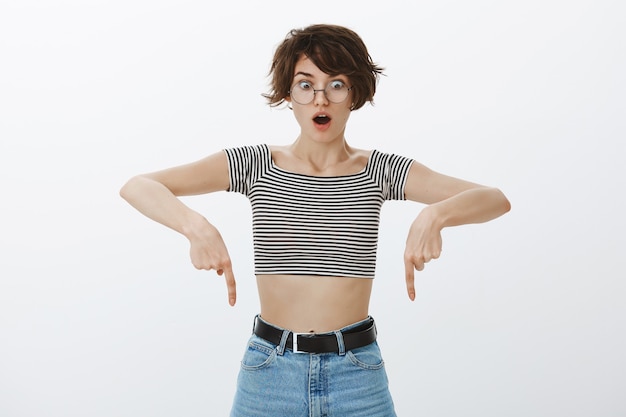 Free photo shocked hipster girl in cropped top pointing fingers down