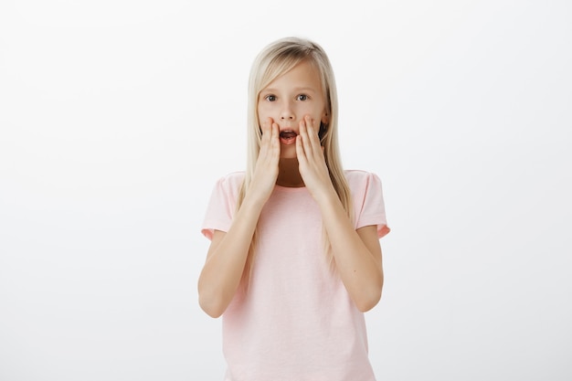 Shocked and impressed blonde little girl gasping, drop jaw amused