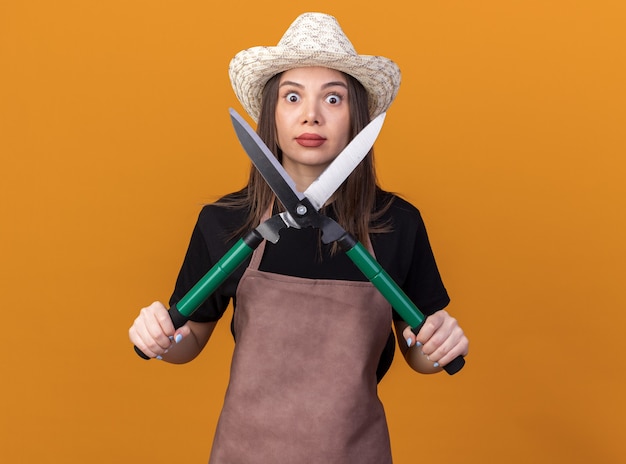 Free Photo shocked pretty caucasian female gardener wearing gardening hat holding gardening scissors