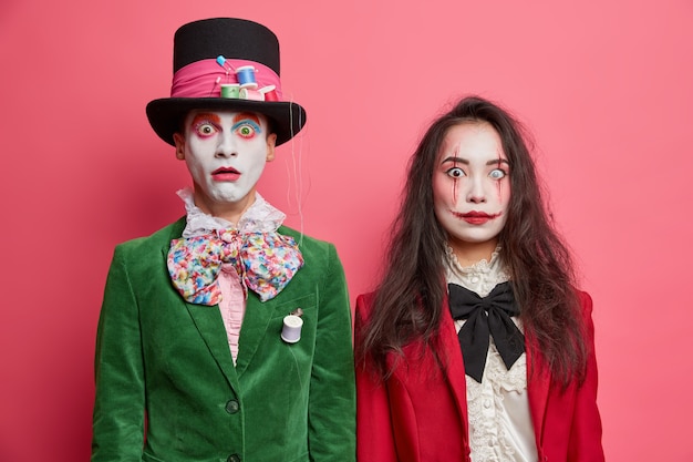 Free Photo shocked scary couple celebrate halloween have professional makeup and wear costumes pose next to each other against pink wall