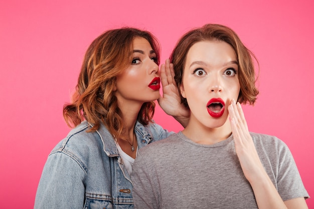 Shocked two women friends gossiping.