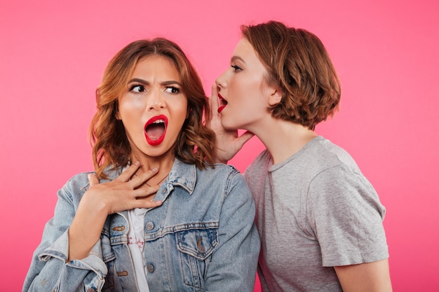 Shocked two women friends gossiping.