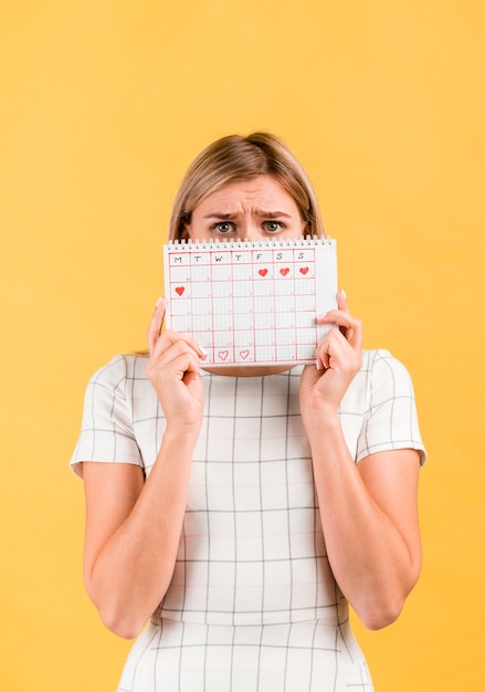 Free Photo shocked woman covering her face with period calendar