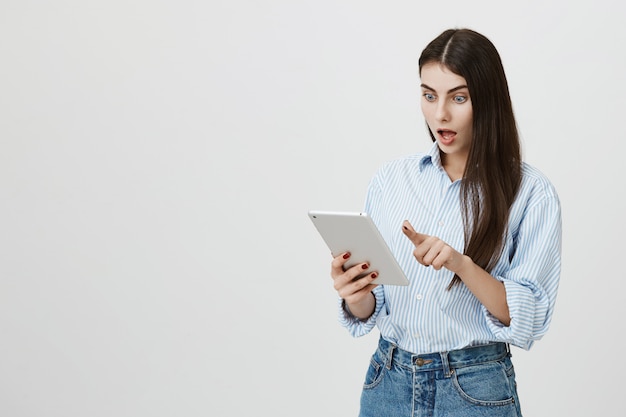 Shocked woman staring excited at digital tablet display