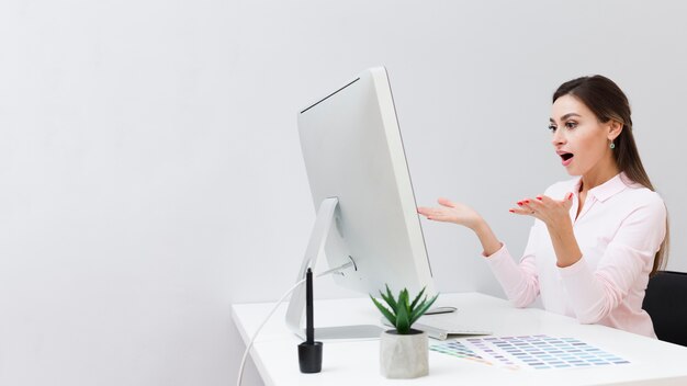 Shocked woman at work looking at computer with copy space