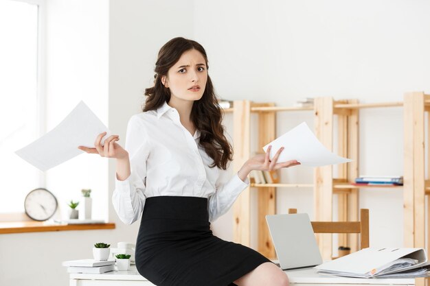 Shocked young business woman surprised by reading unexpected news in document amazed woman office worker feeling stunned baffled by unbelievable information in paper about debt or dismissal