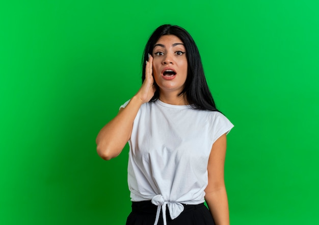 Shocked young caucasian girl puts hand on face looking  